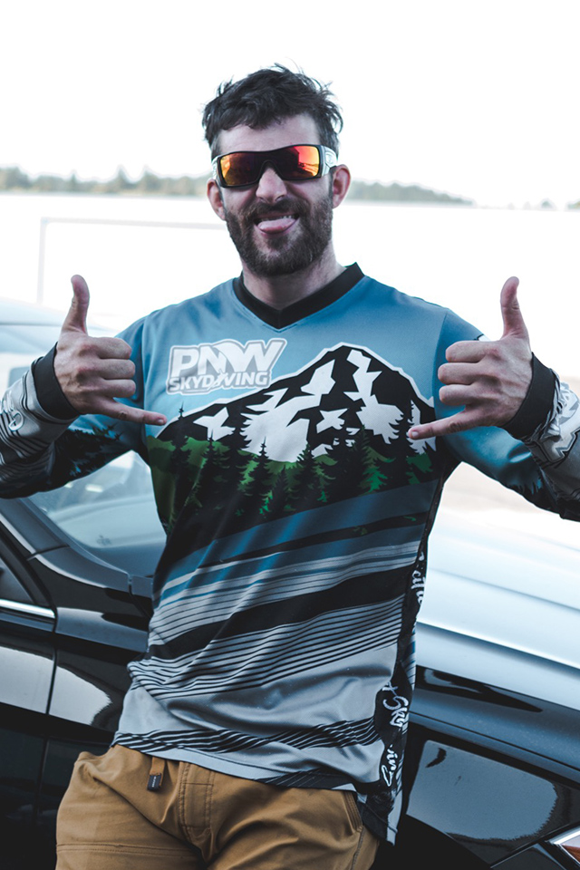 Kevin Rieschel smiles at camera wearing PNW Skydiving jersey