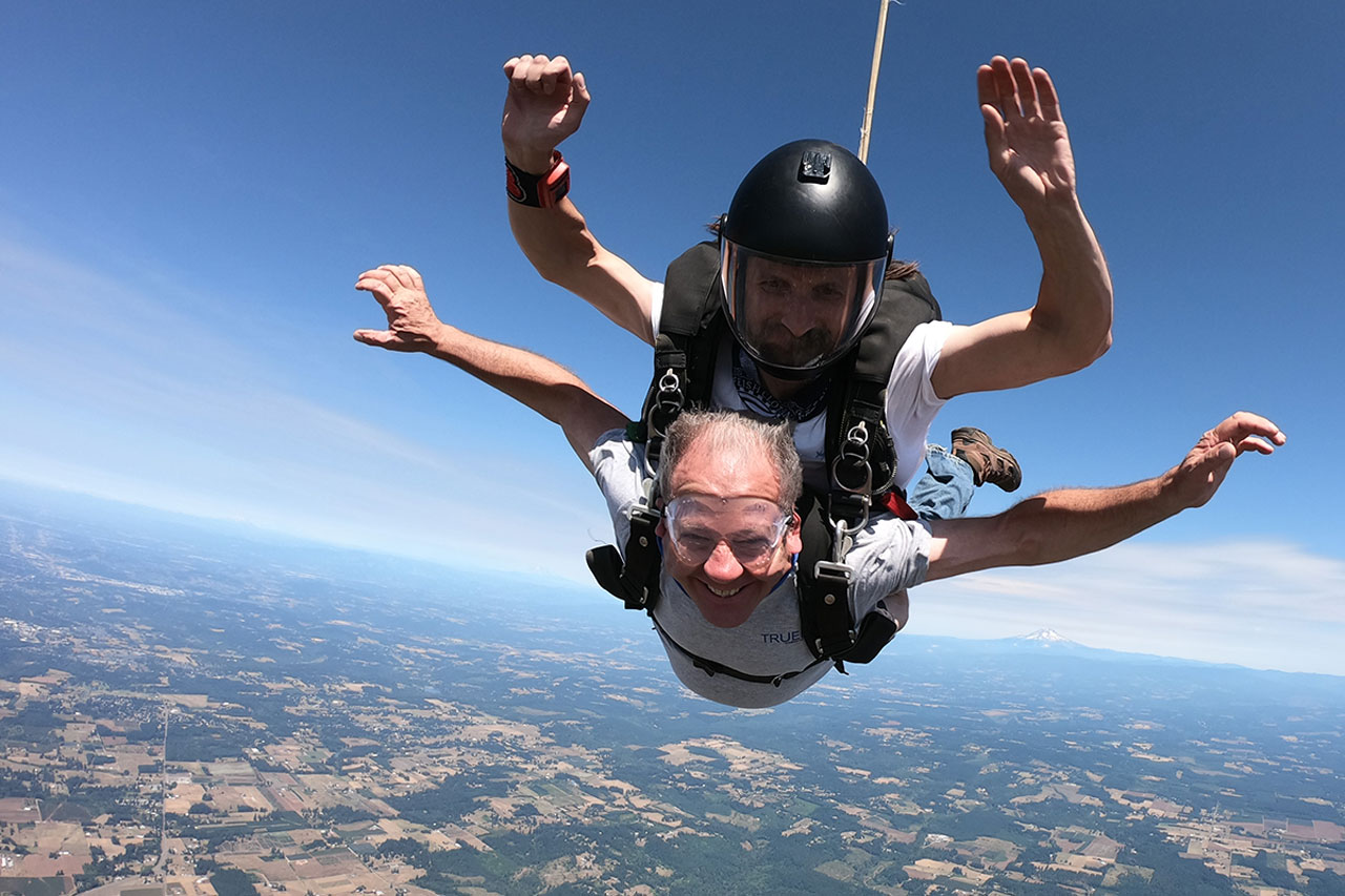 older gentleman smiles in freefall while skydiving